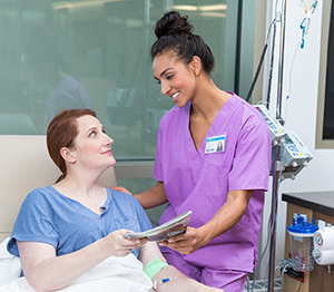 Healthcare provider caring for woman having infusion treatment.